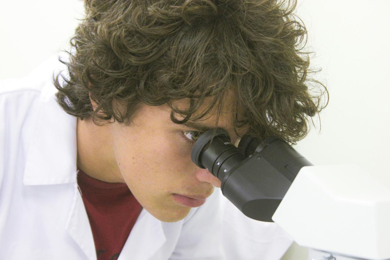 A young scientist examines through a microscope.